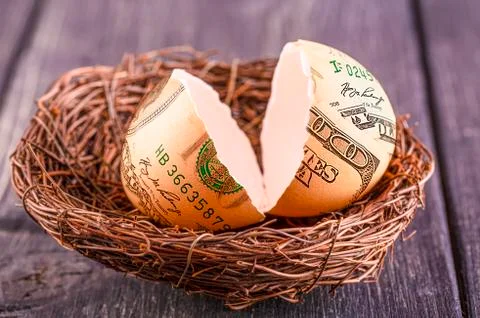 Broken egg with the image of dollars in nest. Selective focus Stock Photos