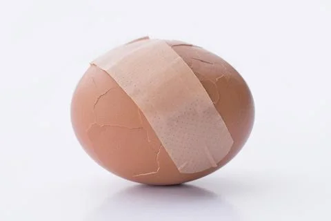 Broken egg with plaster on the white background Foto stock