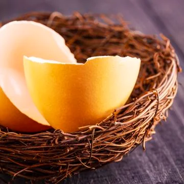 The broken egg shells in the nest on the old wooden background. Stock Photos
