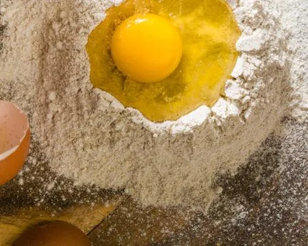 Broken egg on top of a bunch of white rye flour. Preparation of dough or brea Stock Photos