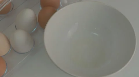 Broken egg with yolk and egg white on white board, with egg shells and whole Stock Footage 43225651