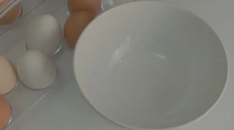 Broken egg with yolk and egg white on white board, with egg shells and whole Stock-Footage 43810865