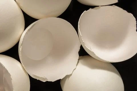 Broken eggs close up image. Shell fragments or shatters on black kitchen tabl Photos