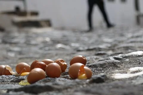 Broken eggs lying on a rough cobblestone pavement Stock Photos