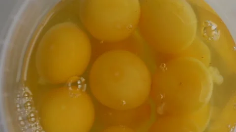 Broken eggs rotate in a plastic bucket close-up. Real time, top view, natural li Stock Footage 142241603