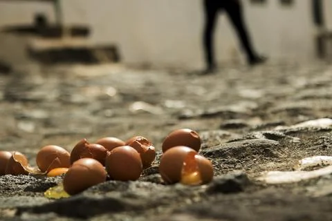 Broken eggs spilling yolk on cobblestone street Stock Photos