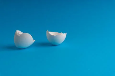 Broken eggshell on the blue background with selective focus 库存照片