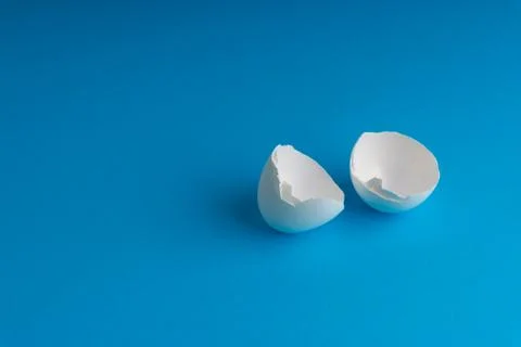 Broken eggshell on the blue background with selective focus Photos