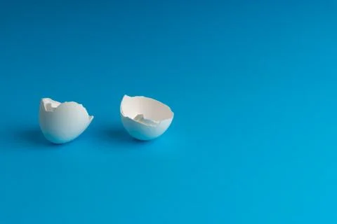 Broken eggshell on the blue background with selective focus Stock Photos