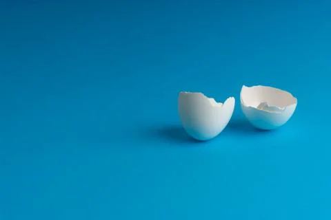 Broken eggshell on the blue background with selective focus 库存照片