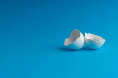 Broken eggshell on the blue background with selective focus Stock Photos
