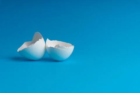 Broken eggshell on the blue background with selective focus Stock Photos