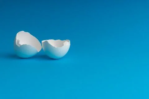 Broken eggshell on the blue background with selective focus Stock-Fotos