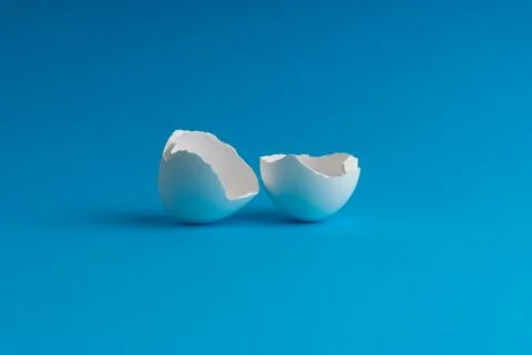 Broken eggshell on the blue background with selective focus 库存照片
