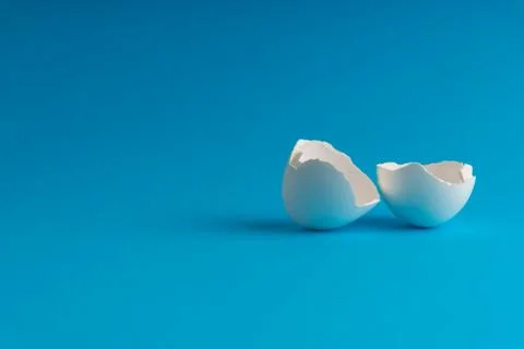 Broken eggshell on the blue background with selective focus 库存照片