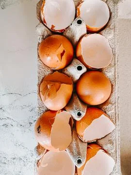 Broken Eggshells in Carton on Marble Background, Top View Stock Photos