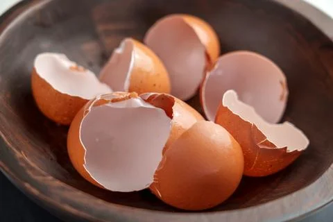 Broken eggshells of chicken brown eggs in wooden kitchen bowl. Organic garbag 스톡 사진