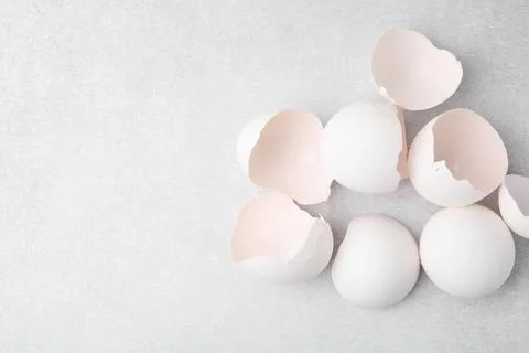 Broken eggshells on grey textured table, top view. Space for text Stock Photos