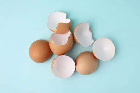 Broken eggshells on light blue background, top view 스톡 사진