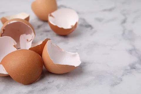 Broken eggshells on light marble table, closeup. Space for text 스톡 사진