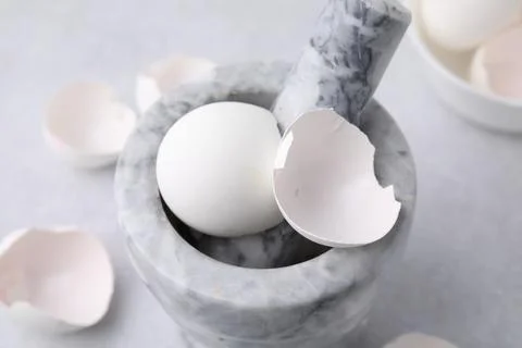 Broken eggshells, mortar and pestle on grey table, closeup Foto stock