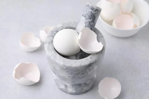 Broken eggshells, mortar and pestle on grey table, closeup Foto stock