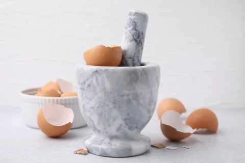 Broken eggshells, mortar and pestle on grey table, closeup Foto stock