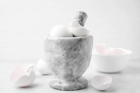 Broken eggshells, mortar and pestle on grey table, closeup Foto stock