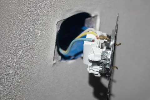 Broken electric socket torn from white wall Stock-Fotos