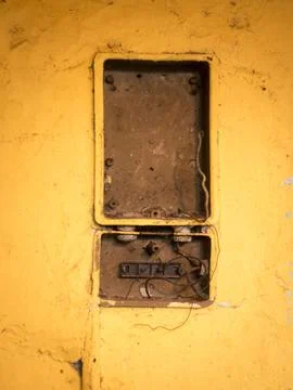 Broken electrical box on yellow wall Stock Photos