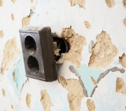 Broken electrical outlet on damaged wall during home renovation Stock Photos