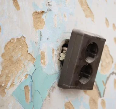 Broken electrical outlet on damaged wall during home renovation Stock Photos