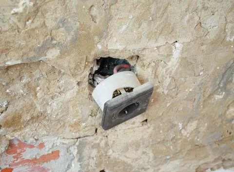 Broken electrical outlet on damaged wall during home renovation Stock Photos