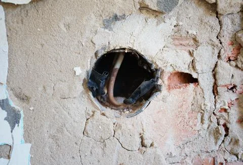 Broken electrical outlet on damaged wall during home renovation Stock Photos