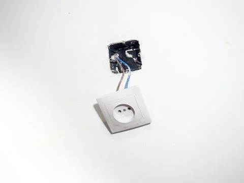 Broken electrical socket on the wall. Disassembled device. White wall with .. Stock Photos