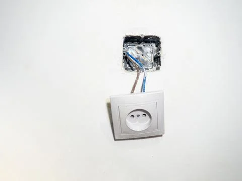 Broken electrical socket on the wall. Disassembled device. White wall with .. Stock Photos
