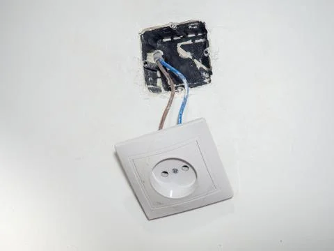 Broken electrical socket on the wall. Disassembled device. White wall with .. Stock Photos