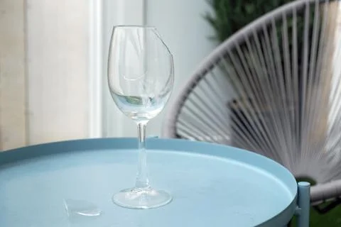 Broken empty goblet. A glass goblet on a leg stands on a small table on the t Stock Photos