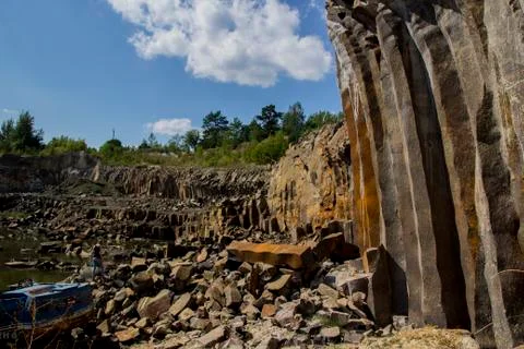 Broken excavator and basalt columns rocks. Heavy industry. Stone excavation Stock Photos