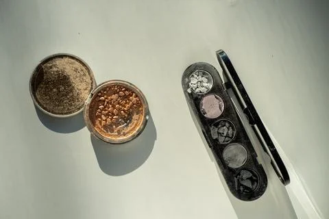 Broken eyeshadow palettes on a white table. Decorative cosmetics Stock Photos