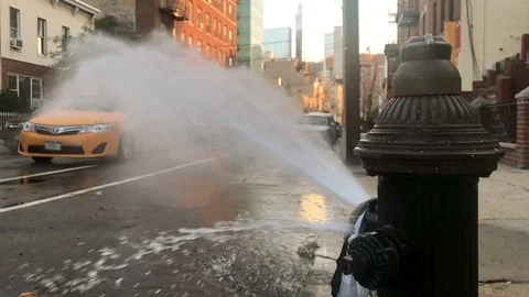 Broken fire hydrant spraying water street taxi cab in summer New York City NYC Stock Footage