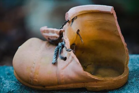 Broken flowerpot in shape of boot. Nostalgic feeling from old thing. Stock Photos