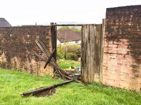 Broken gate in the wall of a garden  Stock Photos
