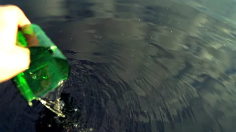 Broken glass bottle in hand from lake. Marine debris. Glass pollution in lake. 動画素材 324953537