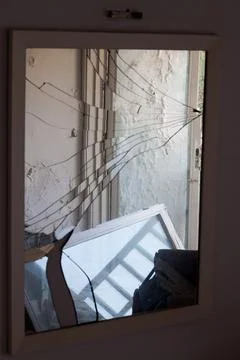 Broken glass with cracks and reflection of abandoned room. The mirror shatter Stock Photos
