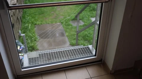 Broken glass door with long spiderweb cracks overlooks wet metal stairs and gree Stock Footage 307700631