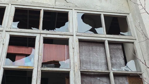 Broken glass windows on an old abandoned building facade with cracked peeling Vídeos de archivo 329762624