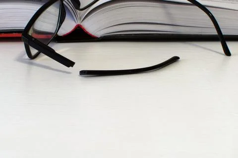 Broken glasses on open book Stock Photos
