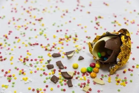 Broken golden chocolate easter eggs with colorful chocolates inside on white  Foto stock