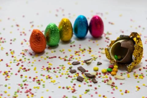 Broken golden chocolate easter eggs with colorful chocolates inside on white  Stock Photos